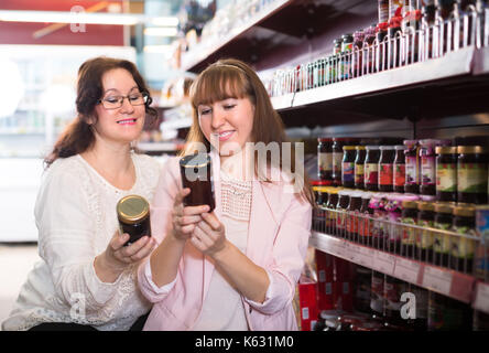 Deux female clients choisissant confiture dans un magasin d'alimentation au point sélective. Banque D'Images