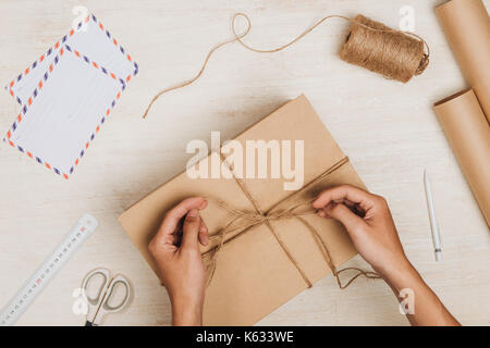 Man wrapping gift. un colis enveloppé dans du papier brun et attachées avec de la ficelle rugueuse Banque D'Images