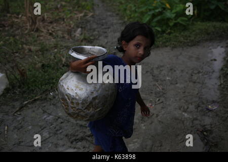 Teknaf, Bangladesh. 10 septembre 2017. Une jeune fille de Rohingya transporte l'eau douce de près de la pompe dans la zone de terrain de No man près de la frontière Bangladesh-Myanmar, à Naikhongchhari, Bandarban. Le réfugié Rohingya marche sur un sentier boueux après avoir traversé la frontière entre le Bangladesh et le Myanmar, à Teknaf. Crédit: Md Mehedi Hasan/Pacific Press/Alay Live News Banque D'Images