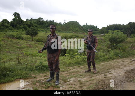 Teknaf, Bangladesh. 10 septembre 2017. Deux membres de la Garde-frontière bangladesh (BDR) en service près de la frontière entre le Bangladesh et le Myanmar, à Teknaf. Le réfugié Rohingya marche sur un sentier boueux après avoir traversé la frontière entre le Bangladesh et le Myanmar, à Teknaf. Crédit: Md Mehedi Hasan/Pacific Press/Alay Live News Banque D'Images