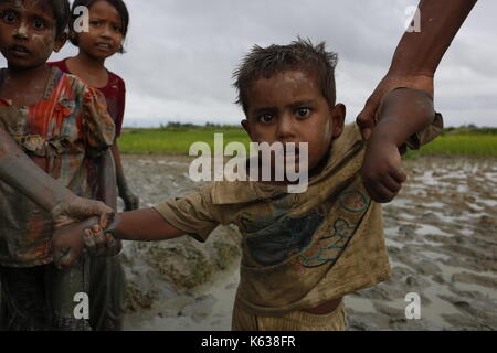 Teknaf, Bangladesh. 09e septembre 2017. Un garçon de Rohingya réagit à la caméra en se promenant sur un sentier boueux après avoir traversé la frontière entre le Bangladesh et le Myanmar, à Teknaf. Le réfugié Rohingya marche sur un sentier boueux après avoir traversé la frontière entre le Bangladesh et le Myanmar, à Teknaf. Crédit: Md Mehedi Hasan/Pacific Press/Alay Live News Banque D'Images