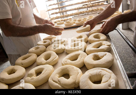 Deux hommes en plaçant des boulangers de la pâte pour les bagels sur une plaque à pâtisserie en table Banque D'Images