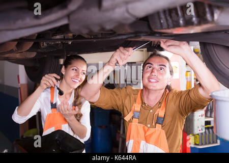 Portrait de deux joyeux la mécanique automobile réparation voiture cassée au garage. selective focus sur l'homme Banque D'Images