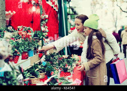 Femme heureuse avec ma petite fille l'achat composition florale en marché de Noël. se concentrer sur la fille Banque D'Images