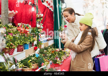 Femme souriante avec sa fille à la parure au marché de noël de conifères avec accent sur la fille. Banque D'Images