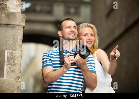 L'homme et de la femme positive de prendre en mains les touristes de l'appareil photo et de photographier à la ville Banque D'Images