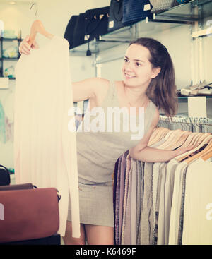 Friendly femme de choisir de nouveaux vêtements à manches longues chemisier shop Banque D'Images