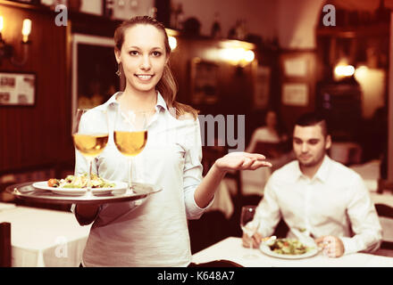 Waitress holding tray with positive verres de vin en bar Banque D'Images