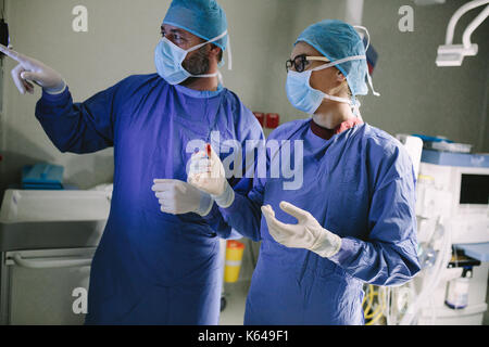 Chirurgien à la recherche médicale à surveiller pendant la chirurgie. Médecin Vérification du moniteur pour l'état de santé du patient. Banque D'Images