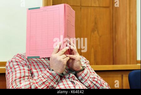 L'ancien infirmier niels h., accusé de plusieurs meurtres et attmepted meurtre de patients, dans la salle d'audience wearing handcuffs et couvrant le visage avec un dossier à la cour de district à Oldenburg (Allemagne), 11 septembre 2014. Dans le monde d'utilisation | Banque D'Images