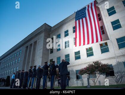 Arlington, États-Unis d'Amérique. 11Th sep 2017. Les premiers intervenants saluer un grand drapeau américain qu'il est déployé sur le côté ouest du pentagone au lever du soleil dans la préparation d'une cérémonie commémorant l'anniversaire des attaques terroristes du 11 septembre au pentagone le 11 septembre 2017 à Arlington, Virginie. l'avion a percuté le bâtiment où le drapeau est déployé. crédit : planetpix/Alamy live news Banque D'Images