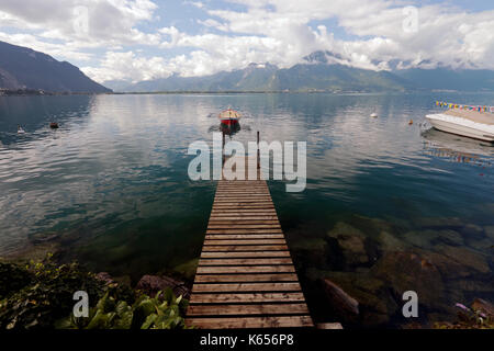 Passerelle, passerelle menant à la jetée ou bateau à rames sur le lac Léman, près de Montreux en Suisse lors d'une journée ensoleillée avec les Alpes en arrière-plan Banque D'Images