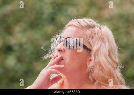 Un modèle femme parution dans son 40's fumer une cigarette à l'extérieur dans le Royaume-Uni Banque D'Images