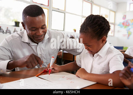 Aider les enseignants de l'école élémentaire girl à son bureau, Close up Banque D'Images