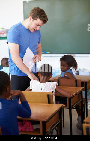 Homme de race blanche d'aider l'enseignant à l'école primaire les écolières Banque D'Images