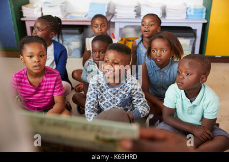 La lecture de l'enseignant livre d'enfants de l'école primaire en classe Banque D'Images