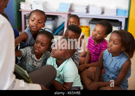 La lecture de l'enseignant livre d'enfants de l'école primaire en classe Banque D'Images