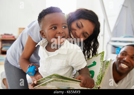 Famille avec jeunes enfants Reading Book In Jeux Ensemble Banque D'Images