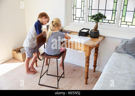 Garçon et fille dans la chambre avec tablette numérique à faire leurs devoirs Banque D'Images