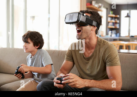 Père et fils jouer jeu sur ordinateur à l'aide de casque de réalité virtuelle Banque D'Images