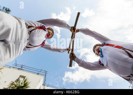 Deux Anglais Hartley Morris men traditionnel en face de l'autre tenant ensemble poteaux en bois. Vue à partir du sol jusqu'à hommes, donnant sur l'afficheur. Banque D'Images