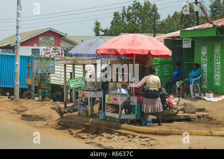 Les femmes s'asseoir à l'ombre des parasols food par route en ville, au Kenya Banque D'Images