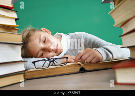 Lycéenne fatigué dormir sur livre. photo de petite fille à l'école autour des livres. l'éducation concept Banque D'Images