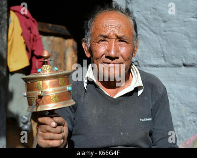 L'homme du vieux Nepali Gurung balance une roue de prière de main tibétaine (roue de la main) avec sa main droite et pose pour la caméra. Banque D'Images