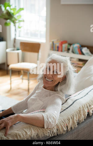 Portrait of smiling woman on sofa Banque D'Images