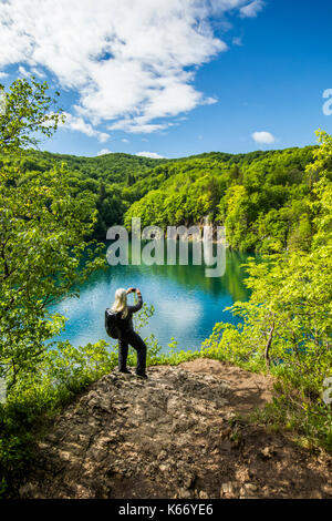 Older caucasian woman photographing waterfall with cell phone Banque D'Images