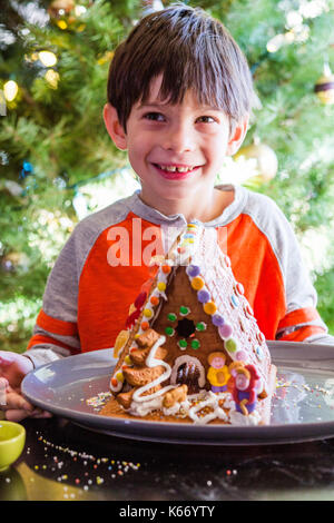 Mixed Race boy with gingerbread house on plate Banque D'Images