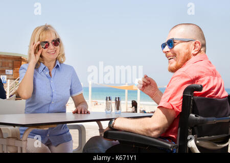 Mobilité l'homme avec sa femme s'amuser tout en étant assis au bar-café près de la plage Banque D'Images