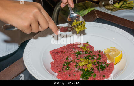 Femme chef de la préparation steak tartare en cuisine avec une sauce spéciale à ristorant Banque D'Images