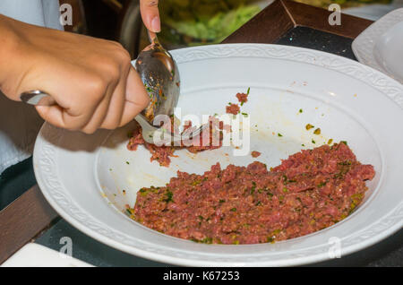 Femme chef de la préparation steak tartare en cuisine avec une sauce spéciale à ristorant Banque D'Images