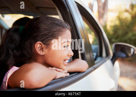 Jeune fille noire à la fenêtre de la voiture hors de vue de côté, smiling Banque D'Images