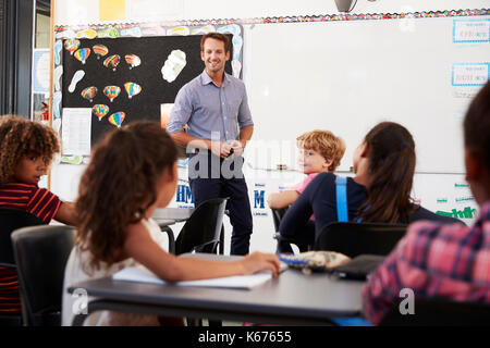 Smiling teacher à l'avant de la classe de l'école élémentaire Banque D'Images
