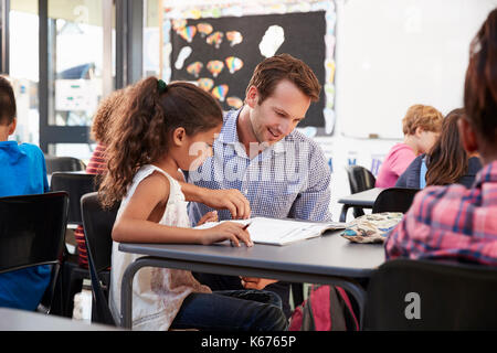 Enseignant travaillant avec jeune écolière à son bureau dans la classe Banque D'Images