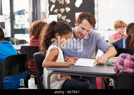 Enseignant travaillant avec jeune écolière à son bureau dans la classe Banque D'Images