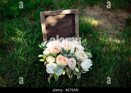 Bouquet de fleurs pour la décoration de la cérémonie du mariage est allongé sur l'herbe verte dans les cercueils en bois-box Banque D'Images