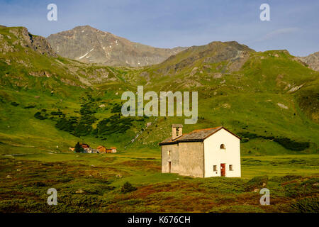 Le Chapel Sun Roc, prairies verdoyantes, buissons, fermes et pistes de montagne à Alp Flix Banque D'Images