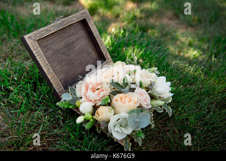 Bouquet de fleurs pour la décoration de la cérémonie du mariage est allongé sur l'herbe verte dans les cercueils en bois-box Banque D'Images