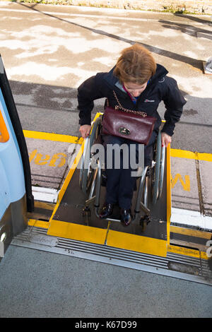 Utilisateur en fauteuil roulant / personne en fauteuil roulant de monter à bord d'un train / entrer dans un compartiment de train à l'aide d'une rampe prévue à la gare. Banque D'Images