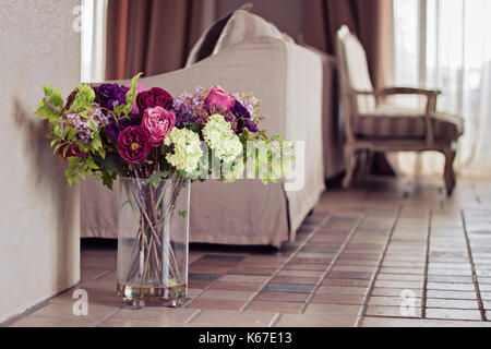 Vase rempli de fleurs artificielles dans un salon Banque D'Images