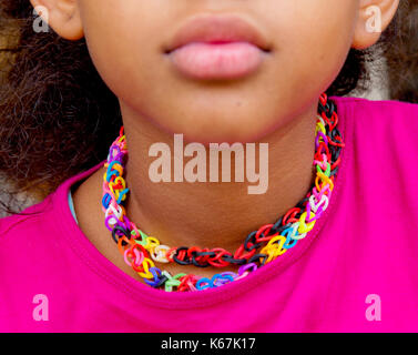 Petite fille avec un collier fait avec des bandes en caoutchouc coloré loom Banque D'Images