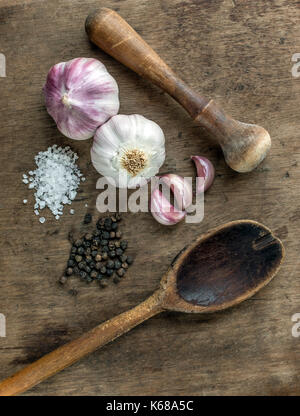 Vue de dessus d'épices et une cuillère de cuisine en bois et le mortier et pilon, montrant ensemble l'ail violet, gousses d'ail, poivre noir et blanc, sel sur Banque D'Images