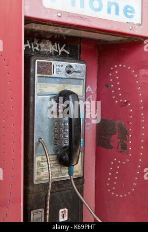 Téléphone public à pièces abandonnées avec coin presse logement. Banque D'Images