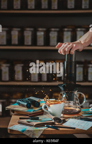 La préparation du café dans un café avec aeropress dynamique splash et la vie toujours avec des cartes et chèques essentials -- cartes, boussole, jumelles. Banque D'Images