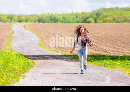 Jeune femme tournant sur route de campagne par brown champs labourés avec sillons en été à l'île d'Orléans, Québec, Canada Banque D'Images