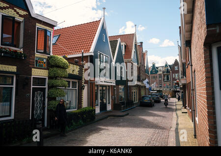 Volendam, Pays-Bas - 26 avril, 2017 : habitant du village de Volendam en vélo en face de la typique des maisons traditionnelles de la pêche néerlandais vill Banque D'Images