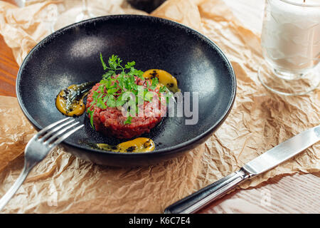 Tartare de boeuf avec un oeuf sur une plaque en pierre. de tomates cerises. romarin. d'épices. Banque D'Images